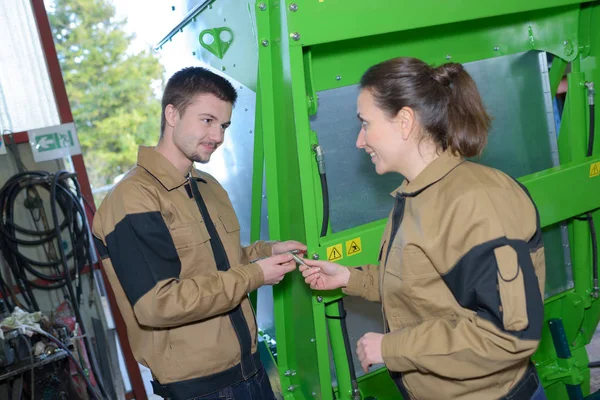 Paar Arbeiter in Overalls in der Nähe von Maschinen in der Fabrik — Stockfoto