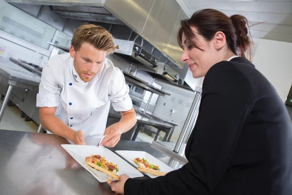 Chef-kok schotel overhandigen aan serveerster in keuken — Stockfoto