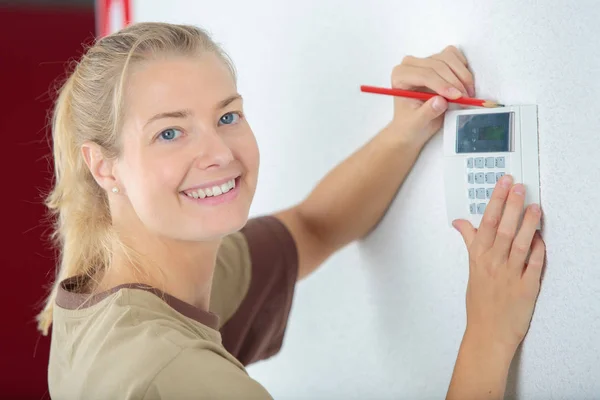 Lady marking position on wall for keypad — Stock Photo, Image