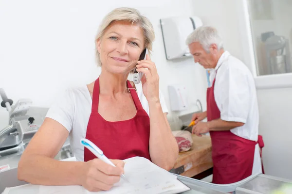 Carnicero propietario teléfono y publicidad — Foto de Stock