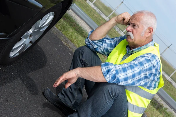 Discouraged retired man unable to change car tyre — Stock Photo, Image
