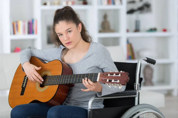 Jovem musicano feminino em cadeira de rodas tocando guitarra clássica — Fotografia de Stock