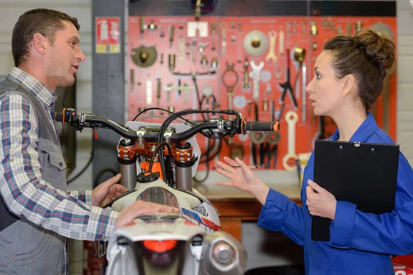 Продавец и покупатель, стоящий в мастерской для мотоциклов — стоковое фото