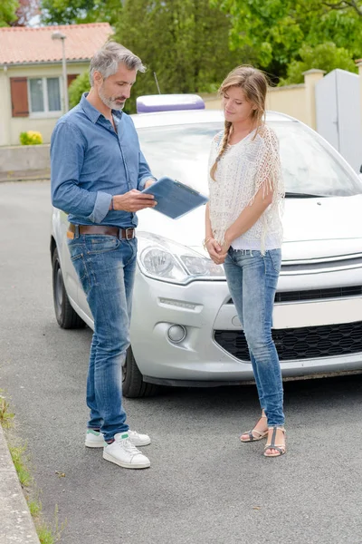 Jovem mulher recebendo uma lição de condução perto do carro — Fotografia de Stock