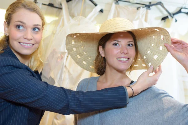 Dvě šťastné ženy přátelé se snaží klobouky — Stock fotografie