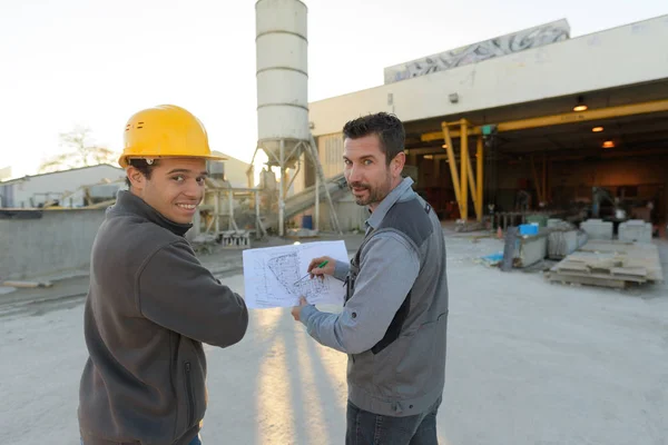 Robotników, patrząc na plany na placu budowy — Zdjęcie stockowe