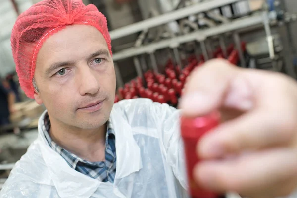 Mittlerer erwachsener Industriearbeiter schaut in Fabrik auf Flasche — Stockfoto