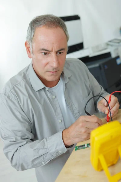 Elettricista maschio che controlla il condizionatore d'aria con il multimetro digitale — Foto Stock