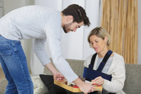 Picture of young man helping ill elderly woman — Stock Photo, Image