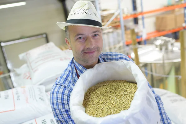 Trabalhador segurando saco cheio de grãos de café — Fotografia de Stock