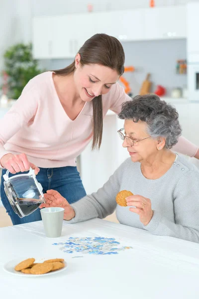 Meisje dienen de bejaarde vrouw met koffie — Stockfoto