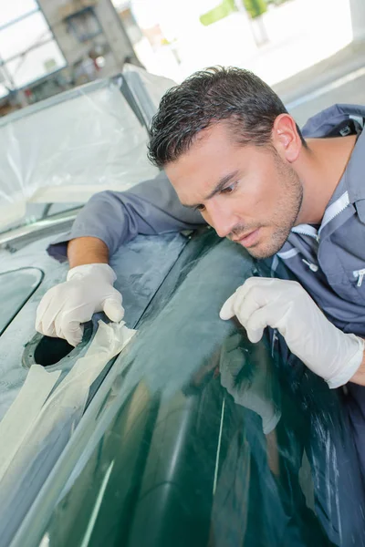 Polijsten van auto en jonge man — Stockfoto