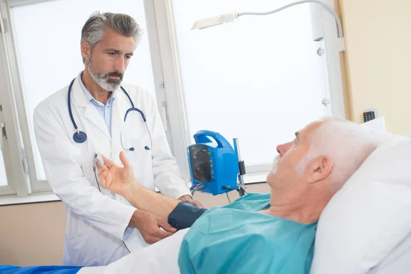 Médico medición de la presión arterial del hombre de edad avanzada — Foto de Stock