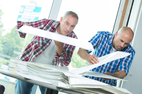 Twee werknemers kijken door de stapel papier — Stockfoto