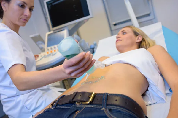 Enfermera chorreando gel lubricante en el abdomen de las mujeres para ultrasonido —  Fotos de Stock