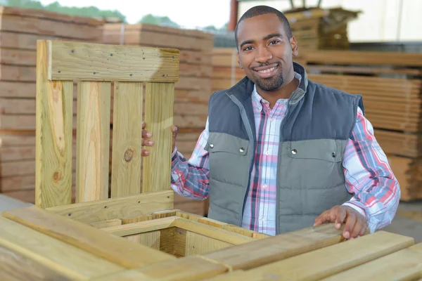 Homem sorridente perfuração e medição de madeira para deck — Fotografia de Stock