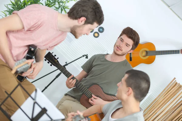 Szczęśliwi przyjaciele grający na gitarze i słuchający muzyki w domu — Zdjęcie stockowe