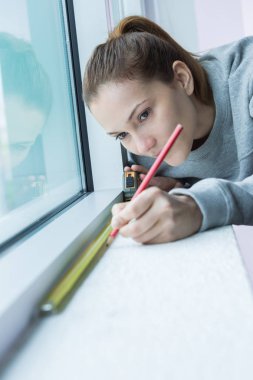 female worker measuring window glass clipart