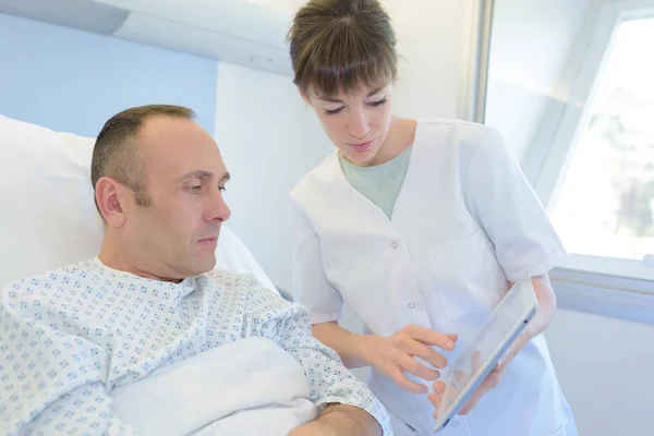 Kvinnlig sjuksköterska hand tar om mannen i sängen — Stockfoto