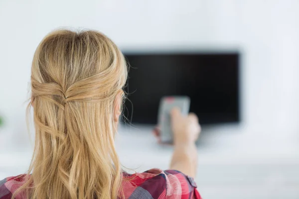 Ung kvinna tittar på TV i rummet — Stockfoto