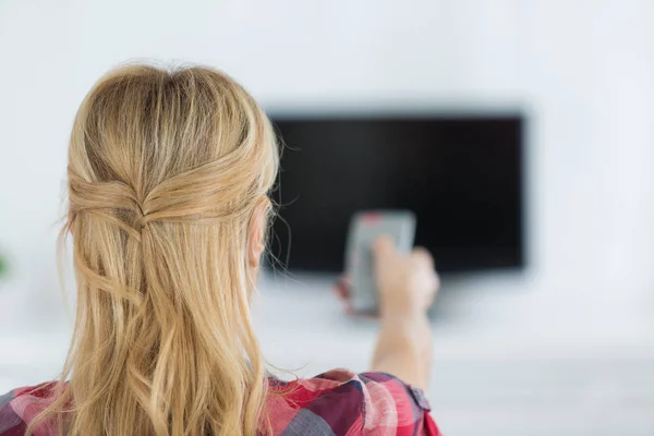 Młoda kobieta ogląda telewizję w pokoju — Zdjęcie stockowe