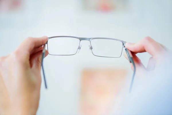 Manos sosteniendo un par de anteojos — Foto de Stock