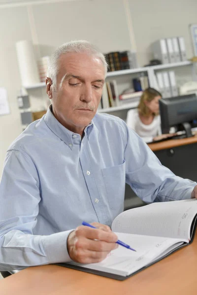 Leitender Büroangestellter schreibt in sein Tagebuch — Stockfoto