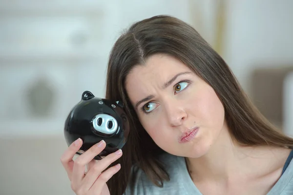Exasperated woman holding piggy bank — Stock Photo, Image