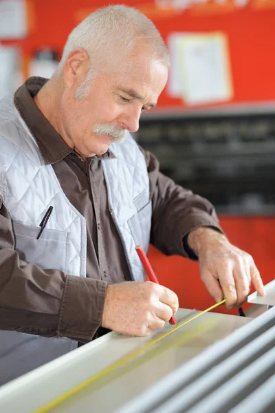 Senior-Handwerker misst einen Gegenstand — Stockfoto