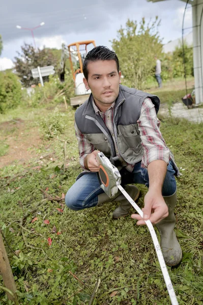 Hombre usando una cinta métrica en el jardín — Foto de Stock