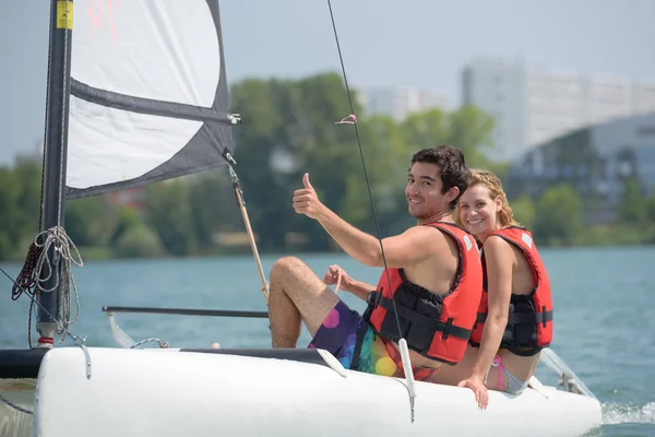 Pareja joven dirigiendo un catamarán — Foto de Stock