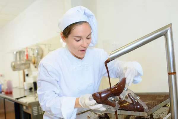 Female chef filling shoe shaped mould with chocolate — Stock Photo, Image