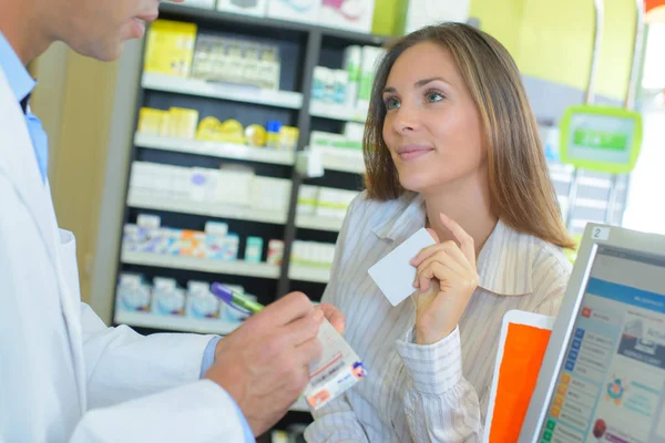 Apothekenkunde gibt eine Karte ab — Stockfoto