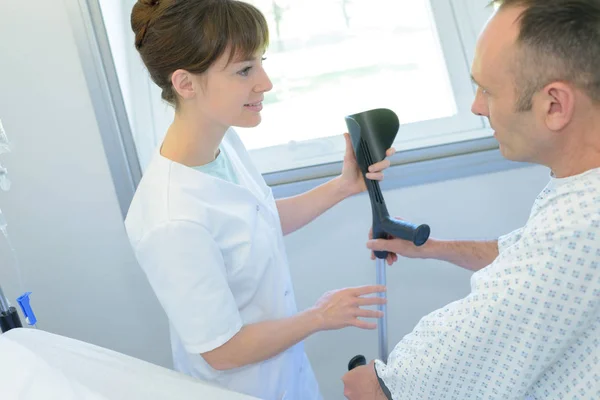 Médecin aidant le patient avec la béquille — Photo