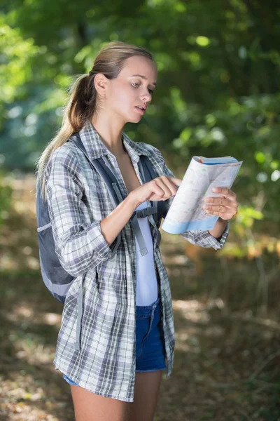 Vrouwelijke wandelaar kijken kaart in bos — Stockfoto