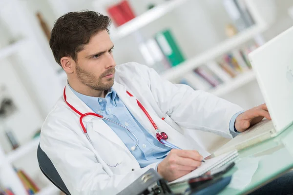 Handsome young doctor at work in his office — Stock Photo, Image