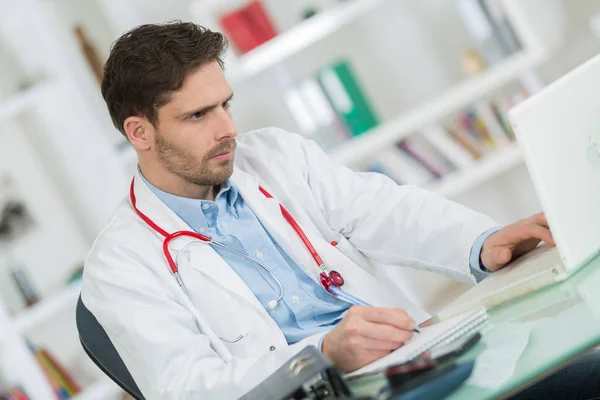 Knappe jonge dokter op het werk in zijn kantoor — Stockfoto