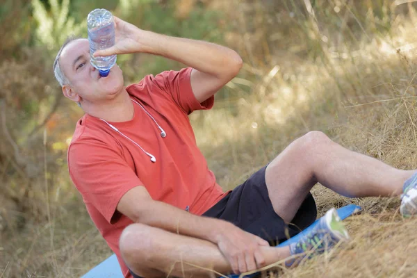 Человек пьет воду после тренировки на открытом воздухе — стоковое фото