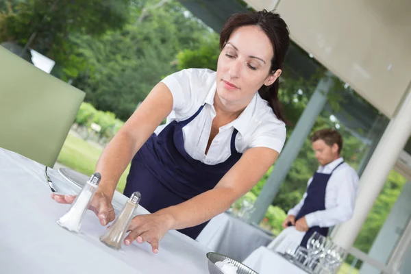 Servitrisen att lägga salt och peppar på bordet — Stockfoto