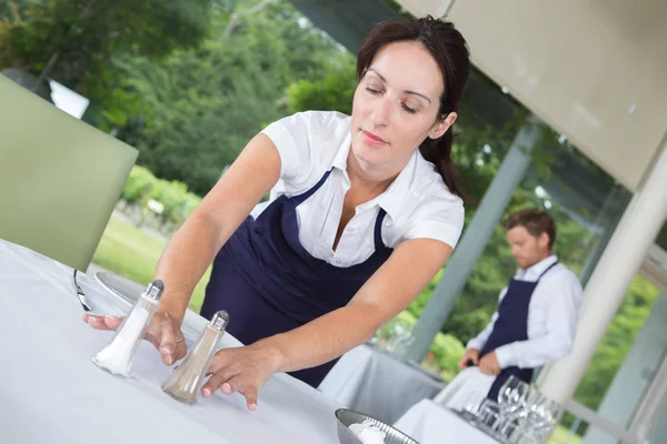 Garçonete colocando sal e pimenta na mesa — Fotografia de Stock