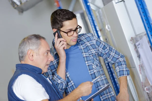 Due lavoratori che parlano e tengono in mano tablet pc e cellulare — Foto Stock