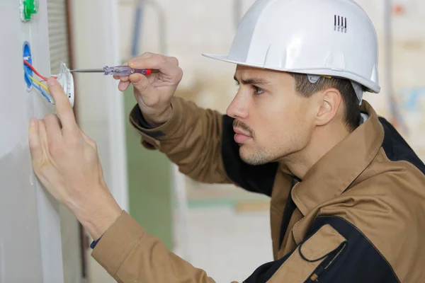 Giovane elettricista che installa presa elettrica a parete con cacciavite — Foto Stock