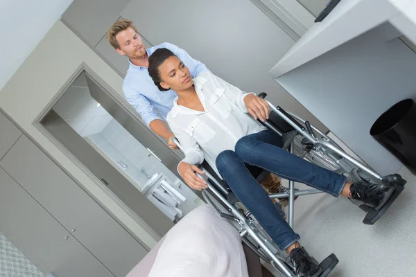 Mari poussant le fauteuil roulant de la femme — Photo