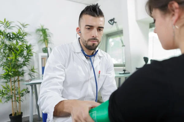 Giovane medico che controlla la pressione sanguigna di una donna incinta — Foto Stock