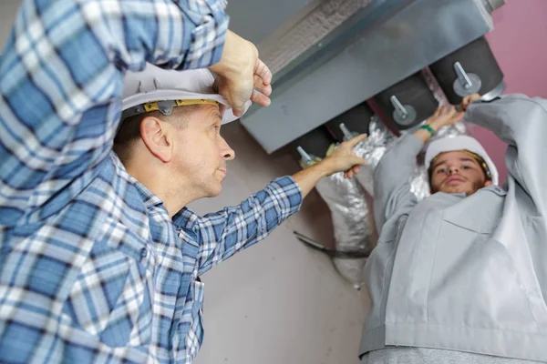 Ouvriers installant des tuyaux de ventilation aérienne — Photo