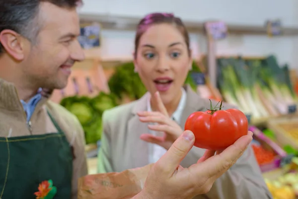 Mujer sonriente eligiendo diferentes frutas en la exhibición de la tienda de alimentos de granja —  Fotos de Stock