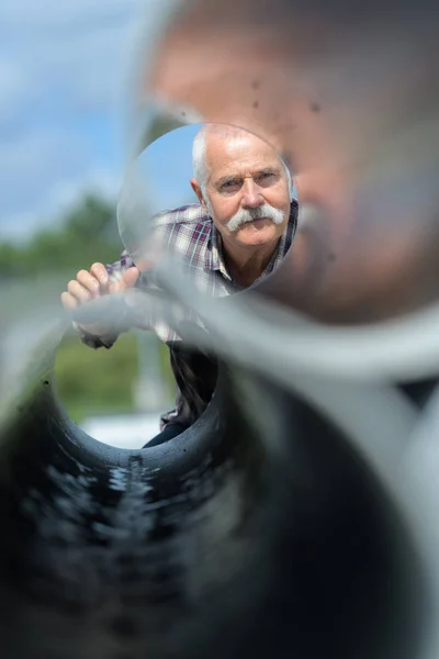 Man op zoek door middel van stalen buizen — Stockfoto