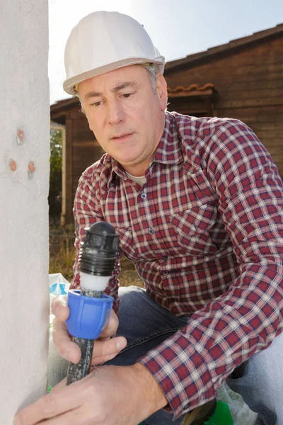Plomero senior que sostiene la tubería de agua al aire libre —  Fotos de Stock