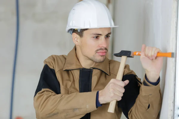 Ung byggmästare håller mejsel och hammare — Stockfoto