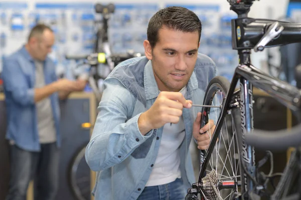 Lächelnder Mann Verkäufer repariert Rad in Sport-Supermarkt — Stockfoto